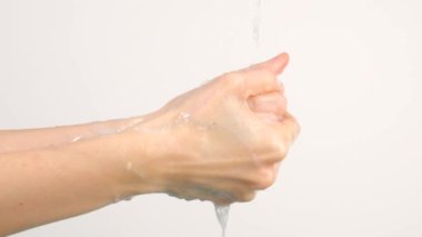 Beyaz arka planda izole edilmiş, akan suyun altında ellerini yıkayan beyaz bir kadın.