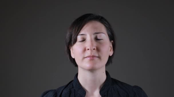 Retrato de uma mulher branca positiva respirando em um fundo cinza — Vídeo de Stock