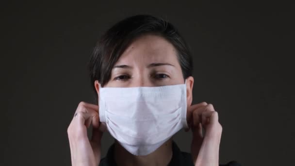 Πορτρέτο μιας λευκής γυναίκας που βγάζει μια λευκή ιατρική μάσκα, προστασία από μεταδοτική ασθένεια, coronavirus — Αρχείο Βίντεο