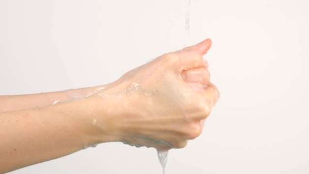 Кавказка моет руки под проточной водой на белом фоне — стоковое видео