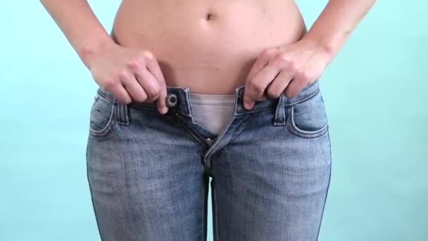 Женщина пытается закрыть слишком узкие синие джинсы. Живот жир и время, чтобы сесть на диету — стоковое видео