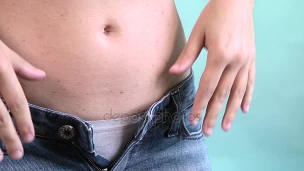 Nahaufnahme eines Mädchens mit dickem Bauch, das kleine Hosen nicht schließen kann — Stockvideo