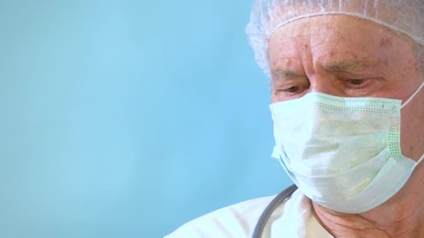 病棟で胸部X線フィルムをチェックするシニア医師 ライトブルーの背景に肺疾患を探している古い白人肺専門家 患者の放射線撮影を保持している深刻な高齢男性外科医 — ストック動画