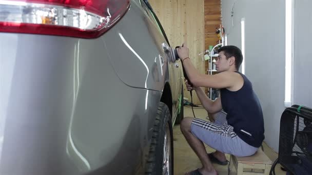 De werknemer polijst een auto cowl met het elektrisch gereedschap. Auto detaillering serie. — Stockvideo
