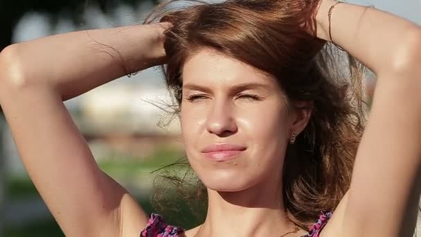 Attraktiv brunett tjej i lila grå klänning. Hon rätar ut håret. Solen sken i håret. — Stockvideo
