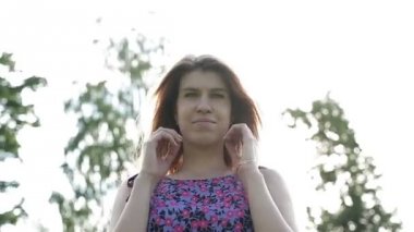 Çiçek elbiseli sarışın kız gülümsüyor ve uzun saçları hareketleri.