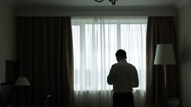 Elegante hombre con una camisa de pie cerca de la ventana — Vídeos de Stock