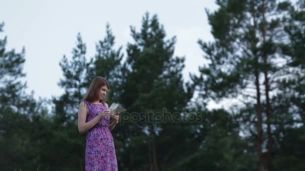 Chica joven mirando fotografías en el fondo del bosque de pinos — Vídeos de Stock