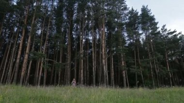 Kır çiçekleri elinde bir buket ile ormanda mutlu genç kız.