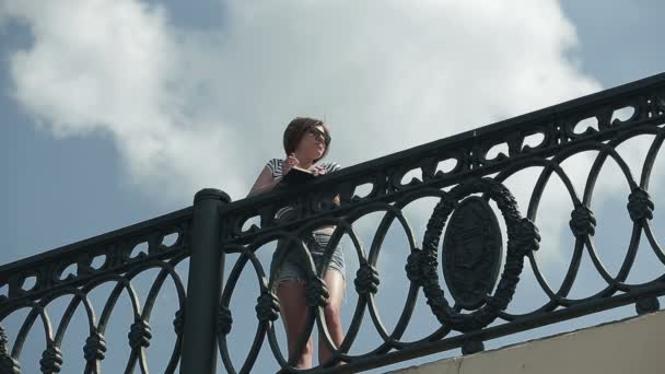 Счастливая девушка в солнцезащитных очках на мосту — стоковое видео