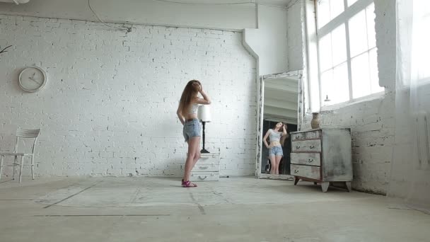 Девушка примеряет новую одежду и смотрит на себя в зеркало — стоковое видео