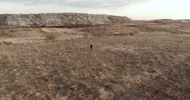 Een man gekleed in zwarte loopt naar de stad-dump — Stockvideo