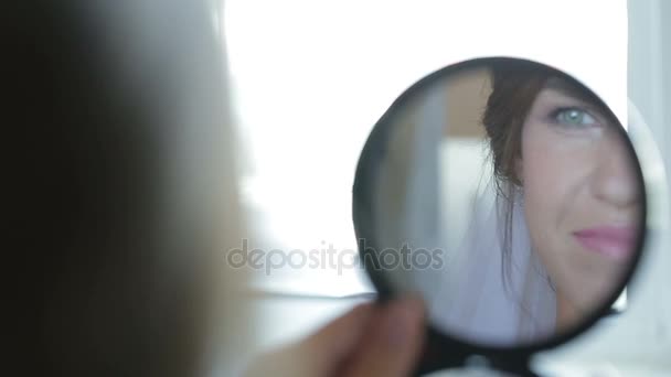 Gentle young bride looks in the mirror. — Stock Video