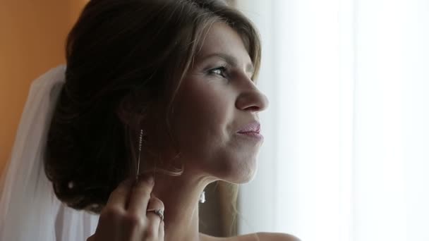 Gyönyörű menyasszony, sötét, göndör haj helyezi a csillogó fülbevaló — Stock videók