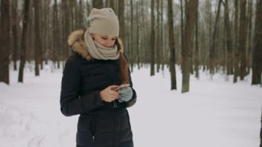 Kış parkta telefon kullanan güzel gülümseyen genç kadın