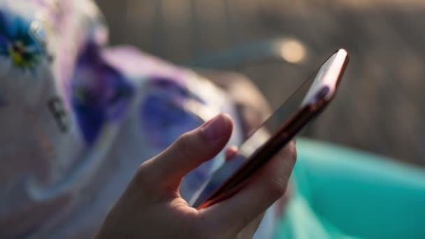 Telefoon bij zonsondergang. Vrouw zijn met behulp van een smartphone bij zonsondergang. — Stockvideo