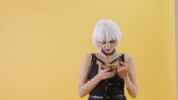 Beautiful young woman texting a message on the smartphone. Yellow background. — Stock Video