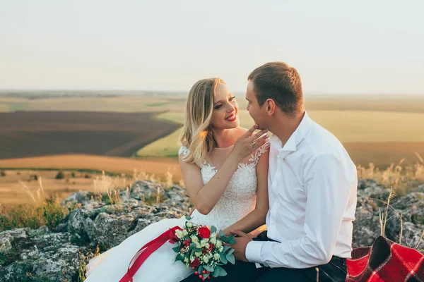 Kayalar üzerine oturan Düğün çifti — Stok fotoğraf