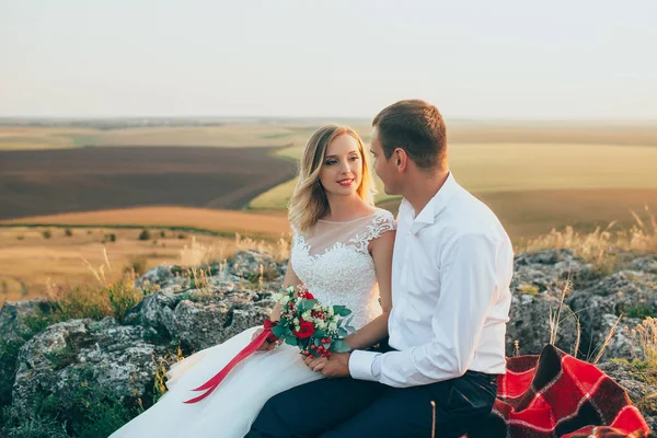 Kayalar üzerine oturan Düğün çifti — Stok fotoğraf