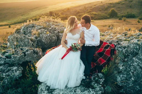 Pareja de boda sentada sobre rocas — Foto de Stock