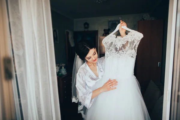Braut hält Brautkleid — Stockfoto