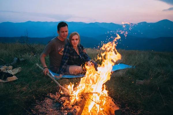 Couple sitting near bonfire