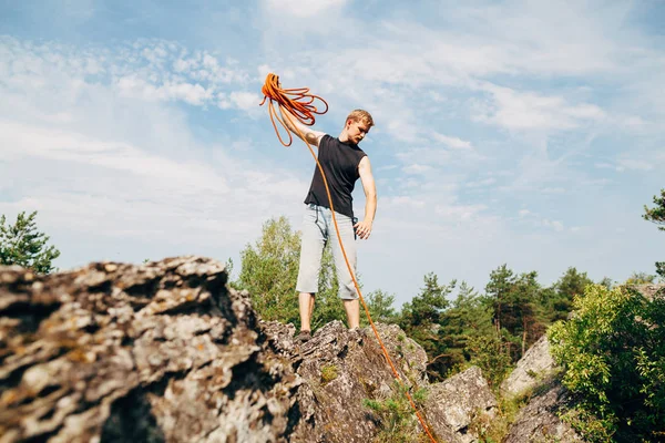 man throwing rope on rock