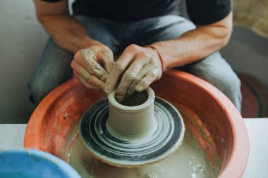 Potter çömlek çarkında seramik demlik yapıyor.