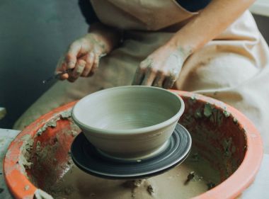 Potter çömlek çarkında seramik demlik yapıyor.