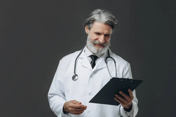 Retrato de médico sênior segurando prancheta em suas mãos — Fotografia de Stock