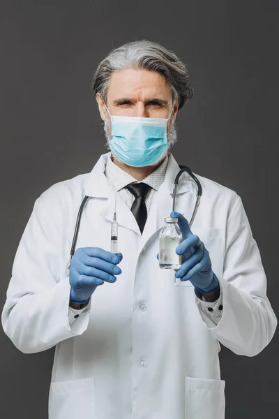 Oude mannelijke arts in handschoenen en medisch masker houdt spuit vast. — Stockfoto