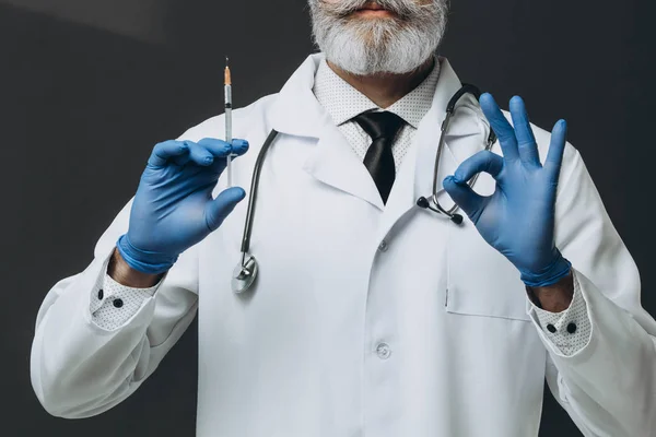 Oude serieuze arts met injectiespuit met vaccin. Klaar om te injecteren. — Stockfoto