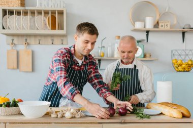 Oğlu ve kıdemli babası mutfakta yemek yapıyor..