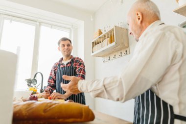 Oğlu ve kıdemli babası mutfakta yemek yapıyor..