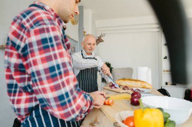 Oğlu ve kıdemli babası mutfakta yemek yapıyor..