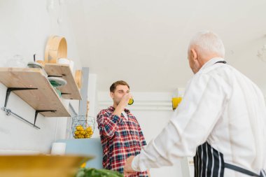 Genç adam ve babası mutfakta yemek pişiriyor.