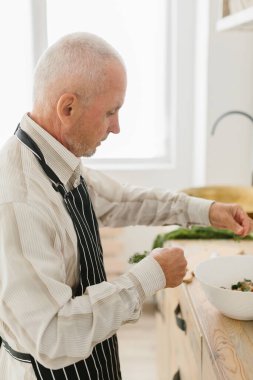 Büyük baba mutfakta salata hazırlıyor.