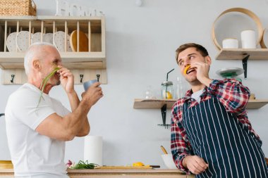 Genç adam ve babası mutfakta yemek pişiriyor.