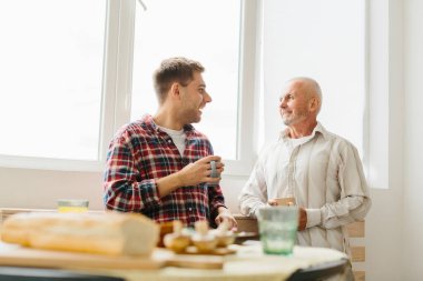 Oğlu ve kıdemli babası evdeki sandalyelerde oturmuş konuşuyor..