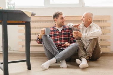 Yetişkin hipster oğlu ve üst düzey baba evde kapalı katta oturan bir portre.