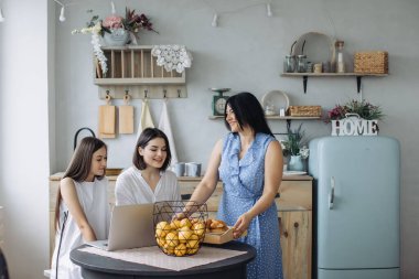 Anne ve kızları mutfakta konuşuyor. 