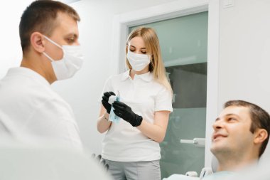 Doktor Dişçi ve asistanı bir diş kliniğinde çalışıyor..