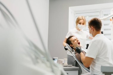 Doktor Dişçi ve asistanı bir diş kliniğinde çalışıyor..