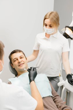 Doktor Dişçi ve asistanı bir diş kliniğinde çalışıyor..