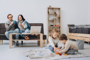Çocuk kız ve erkek kardeş anne evde koltukta, eğleniyor, kardeşler arasındaki dostluk küçük çocuk kız rahatlatıcı süre katta çizim birlikte oynarken aile boş zaman oturma odasında