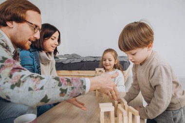 Genç anne ve baba çocuklarla eğitici oyunlar oynuyor.