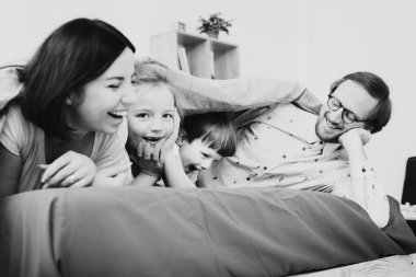 Çocuklu genç ebeveynler hafta sonları yatakta eğleniyor..