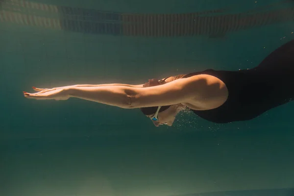 Vrouwelijke Zweminstructeur Een Zwart Zwempak Pet Bril Zwemmen Onder Water — Stockfoto