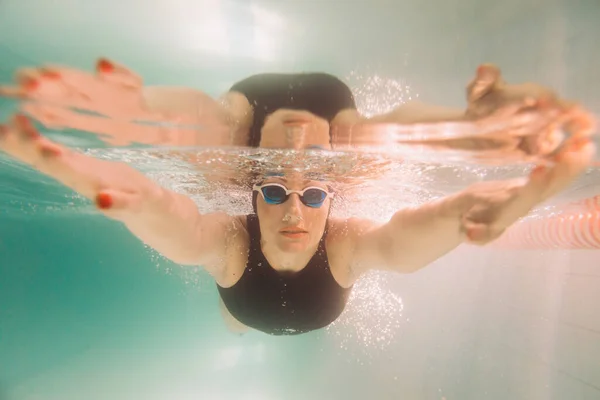 Vrouwelijke Zweminstructeur Een Zwart Zwempak Pet Bril Zwemmen Onder Water — Stockfoto