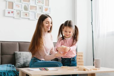 Anne ve kızı oturma odasında masa oyunu oynuyorlar..